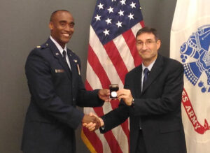 Dr. Ted Thomas, director of CGSC’s Department of Command and Leadership, presents U.S. Air Force Maj. Bishane A. Whitmore with a General of the Army Commemorative U. S. Silver Dollar, the individual award that is part of Whitmore’s earning the Lieutenant Colonel Boyd McCanna “Mac” Harris Leadership Award for the CGSOC Class of 2016.