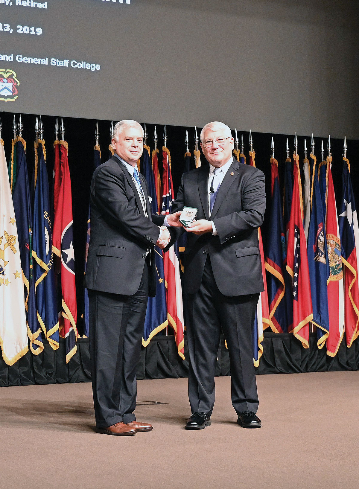 CGSC Foundation President/CEO Rod Cox presents Gen. (Ret.) Carter F. Ham with a silver Colin L. Powell commemorative coin after his presentation of the Powell Lecture for the CGSOC Class of 2020 on Aug. 13, 2019.