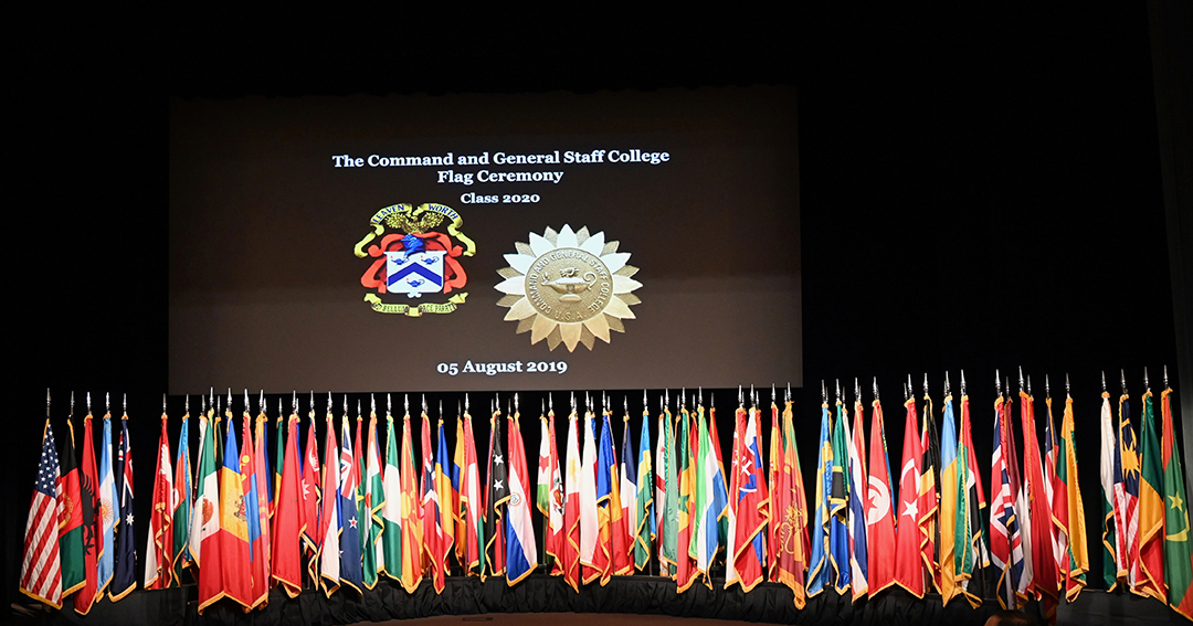 CGSC Class of 2020 flag ceremony image with flags posted on the stage under the video screen with the CGSC crest and the International Officer Badge images displayed