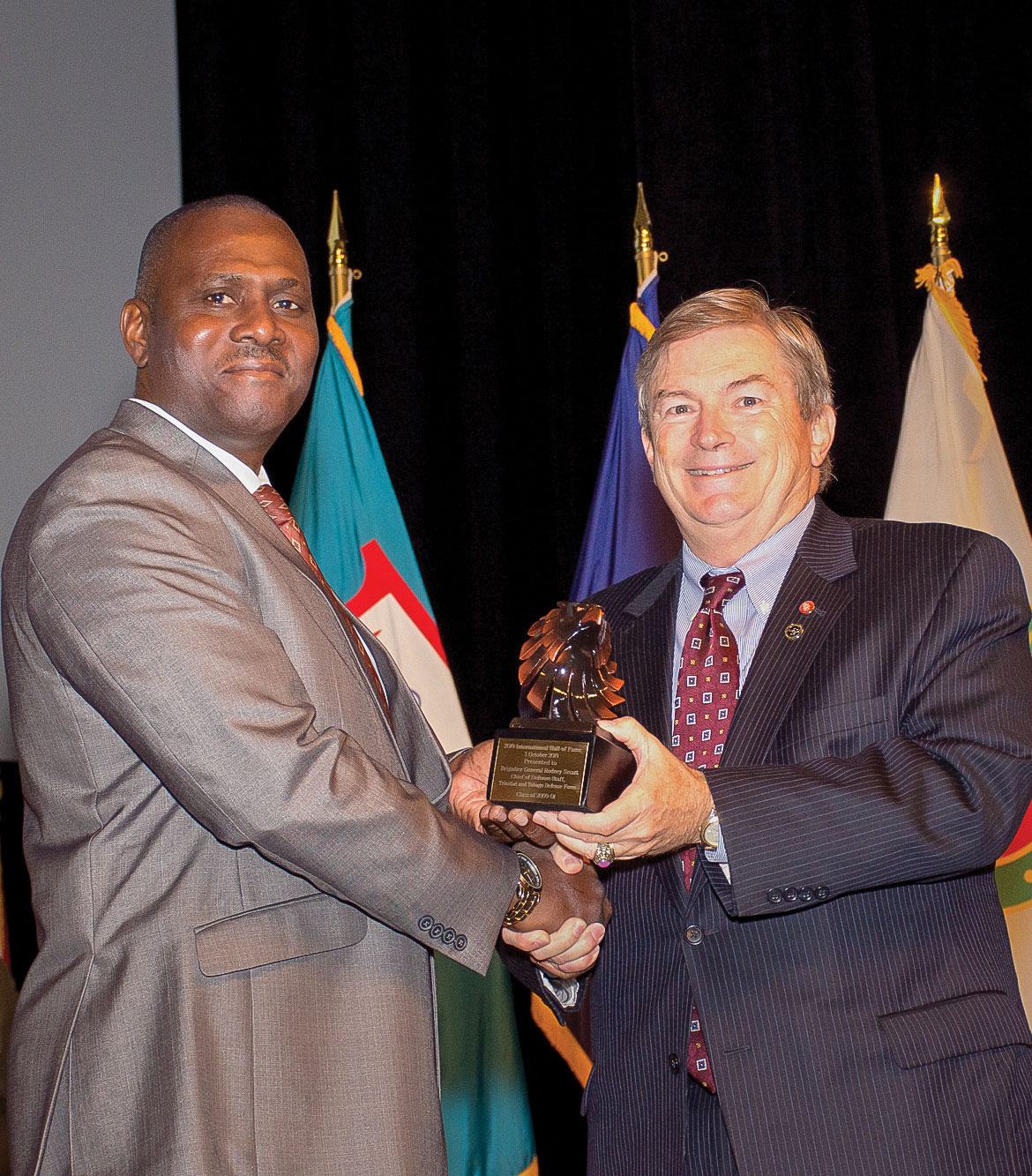 After unveiling his International Hall of Fame portrait, IHOF inductee retired Maj. Gen. Rodney Smart, former chief of Defence Staff of the Trinidad and Tobago Defence Force, receives an eagle statuette gift from Michael Hockley, chairman of the board of the Command and General Staff College Foundation, during his IHOF induction ceremony Oct. 3, 2019, at the Lewis and Clark Center.