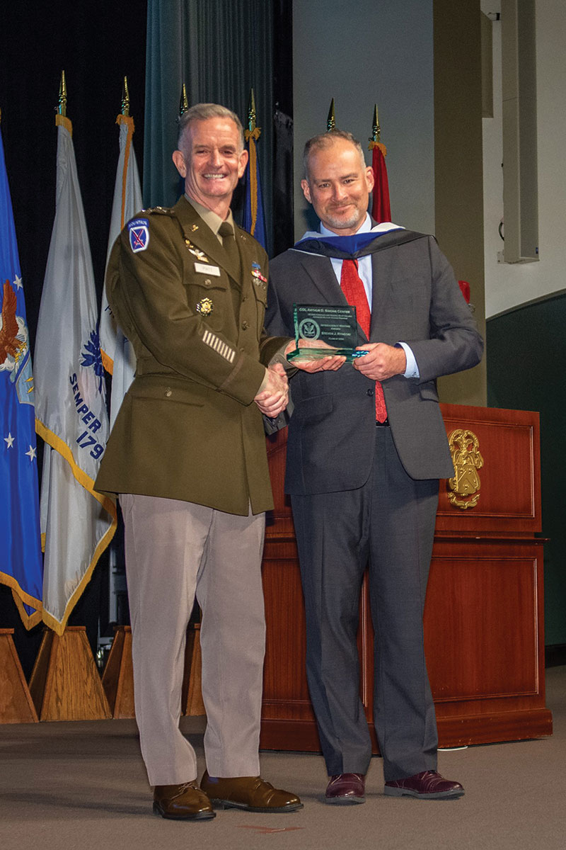 Mr. Steven J. Rynecki, U.S. Agency for International Development (USAID), receives the Simons Center Interagency Writing Award for the best monograph focused on interagency cooperation and coordination from graduation guest speaker Lt. Gen. Walter E. Piatt, Director of the Army Staff, during the SAMS graduation ceremony May 26, 2022.